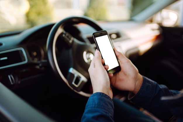 Young man in protective sterile medical mask using phone driving car.