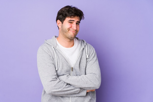 Young man on purple wall unhappy with sarcastic expression.