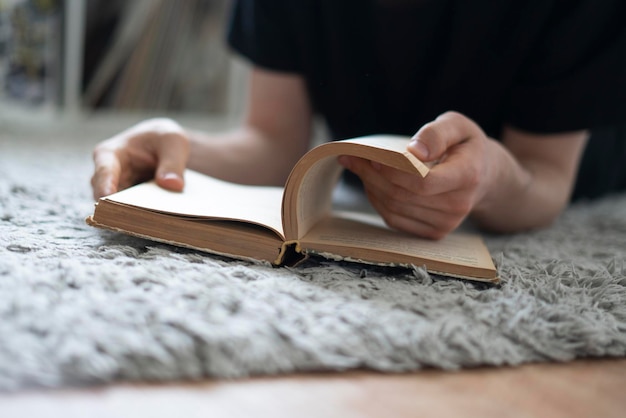 A young man reading the book at home student doing homework