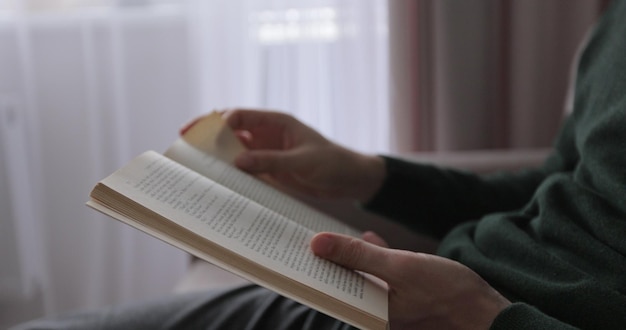 Young man reading a book and turning pages close up Male hands holding a book and flips through the pages