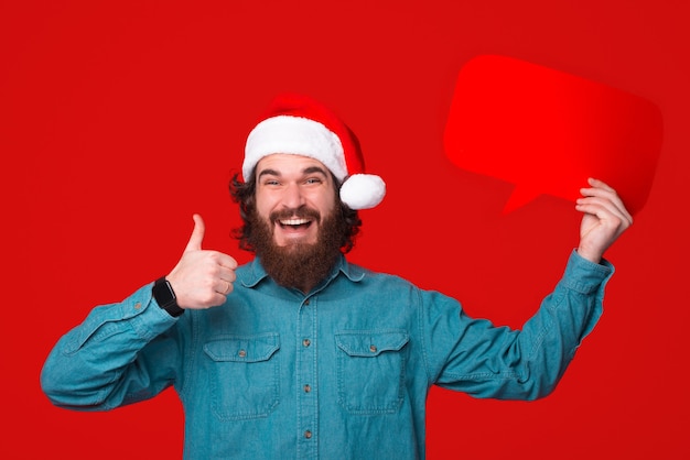 Young man recommends something by showing thumb up and holding a speech bubble