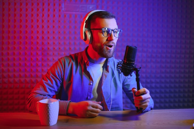 Young man recording or streaming podcast using microphone at his small broadcast studio Content creator