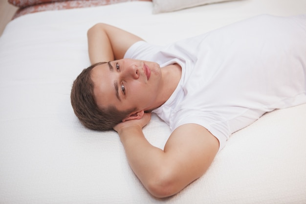 Young man relaxing at home, lying in a bed