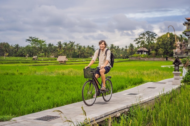 A young man rides a bicycle on a rice field in ubud bali bali travel concept