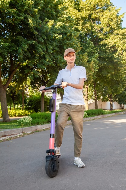 A young man rides an rented electric scooter in the park