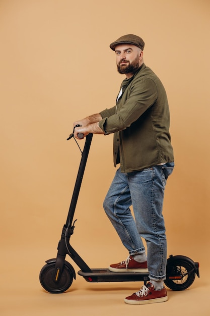 Young man riding electric scooter isolated on background in studio