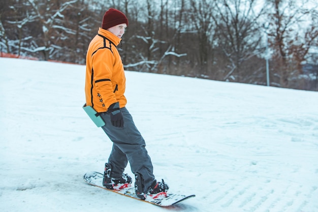 Young man riding snowboard by winter hill