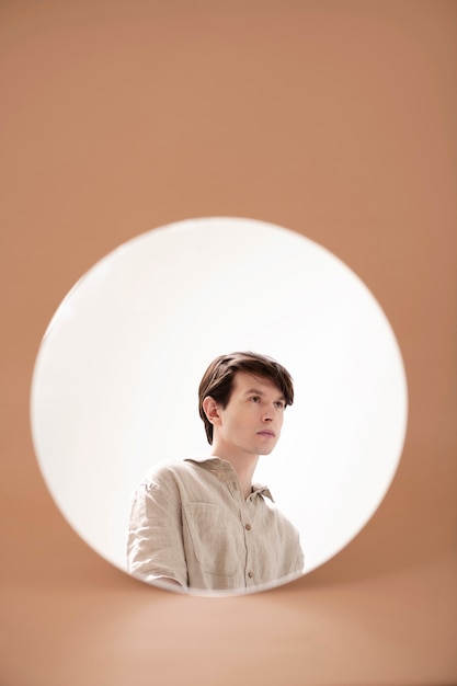 Young man's reflection in circular mirror