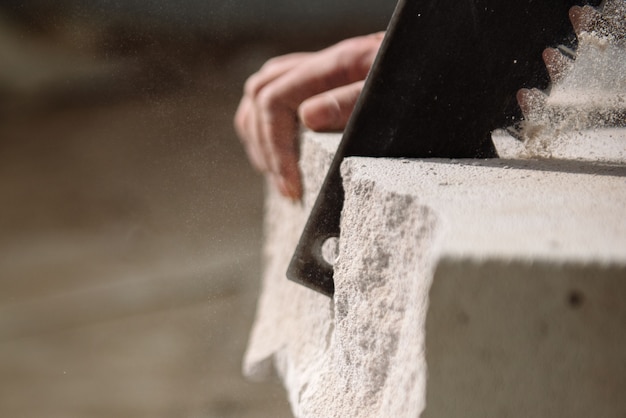 Young man sawing a foam block with a saw