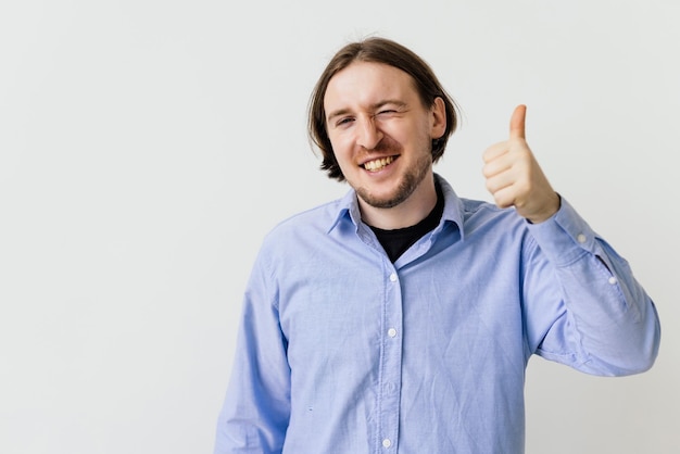 Young man say yes showing thumbs up in approval praise good job smiling approvingly standing on white background