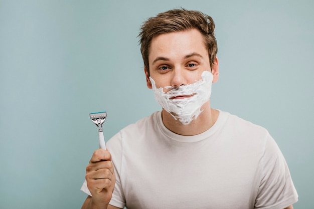 Young man shaving his beard