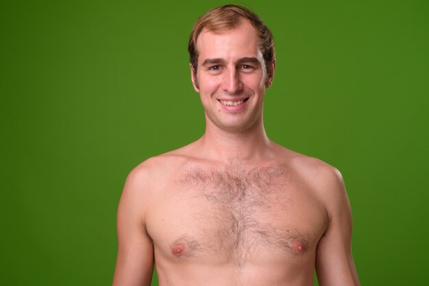 Young man shirtless against green wall