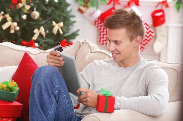 Young man shopping online with credit card at home for Christmas