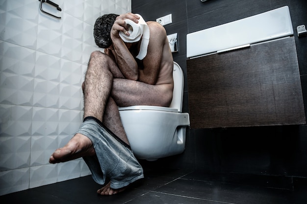 Young man sit on toilet in rest room