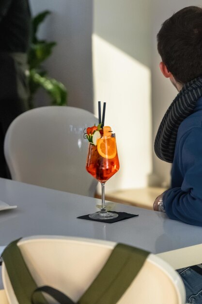 young man sitting in a bar with a spritz on the table