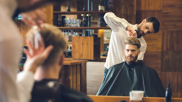 Young man sitting in a barbershop while barber cutting the hair