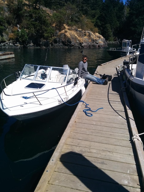 Young man sitting on boat by boardwalk over river