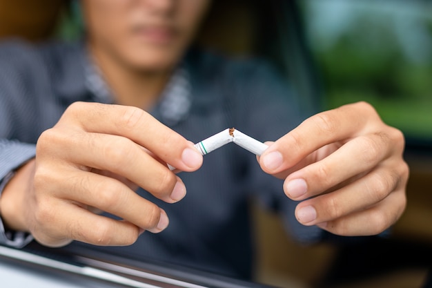 Young man sitting in the car and destroys cigarette