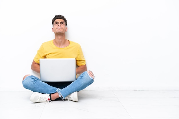 Young man sitting on the floor isolated on white background and looking up