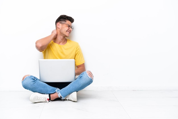 Young man sitting on the floor isolated on white background with neckache