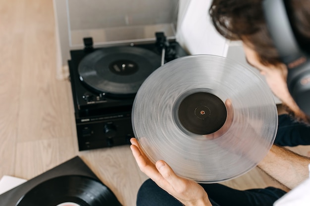 Young man sitting on the floor, listening to music on a vinyl player