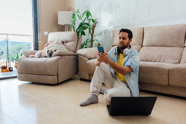 Young man sitting on the floor with laptop and headphones