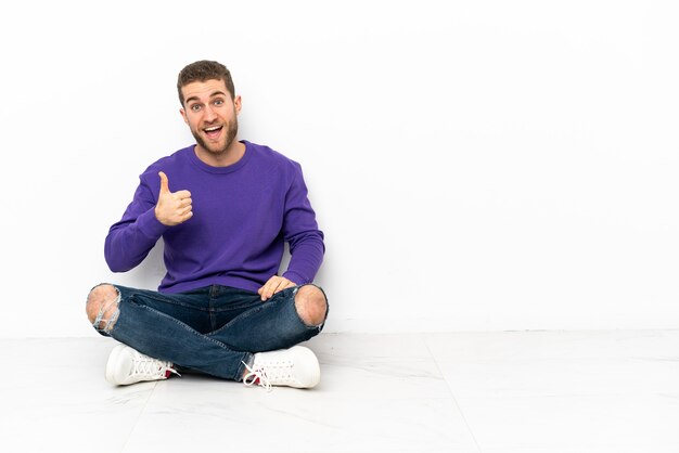 Young man sitting on the floor with thumbs up because something good has happened