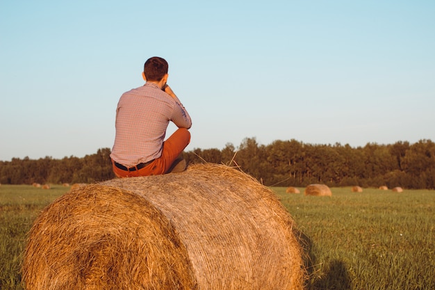 Young man sitting on a hay bale