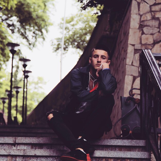 Photo young man sitting outdoors