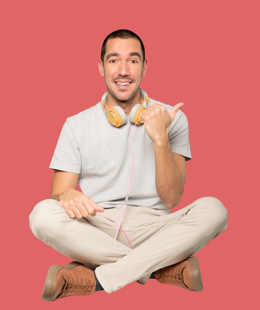 Young man in sitting position with a finger pointing gesture