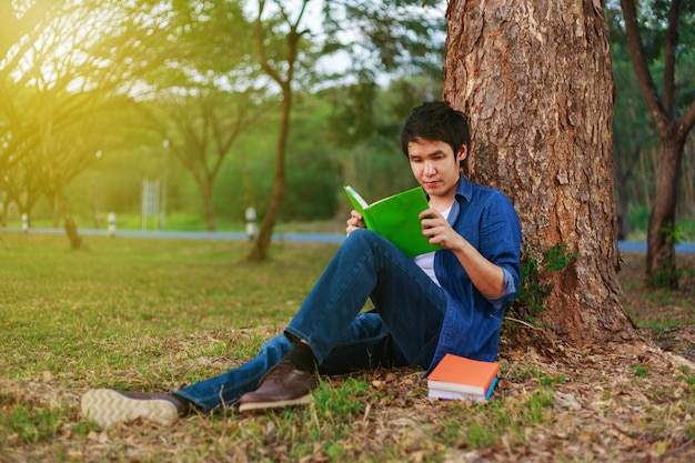 young man sitting and reading a book in park