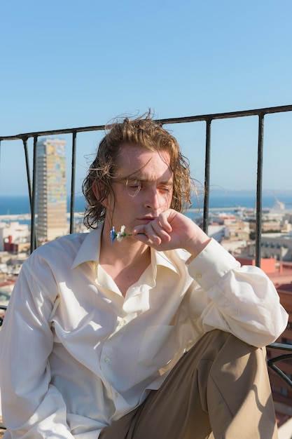 Young man sitting on a rooftop with a city in the background