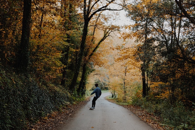 Young man skateboarding in the middle of the forest in autumn in Catalonia