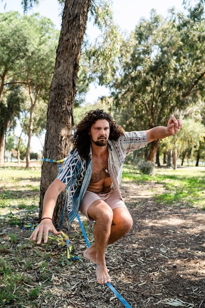 Young man slacklining in the city park during summer day