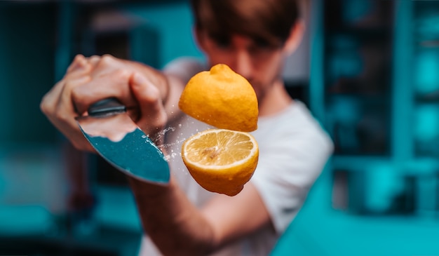 Young Man Slicing With Sharp Knife A Flying Juicy Fresh Lemon