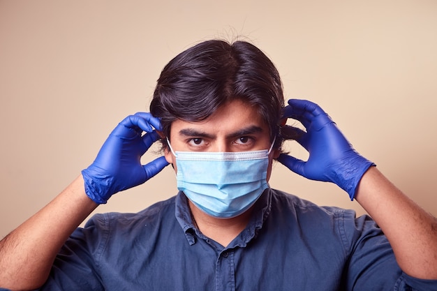 A young man smiles while wearing nitrile gloves with a surgical mask on his face