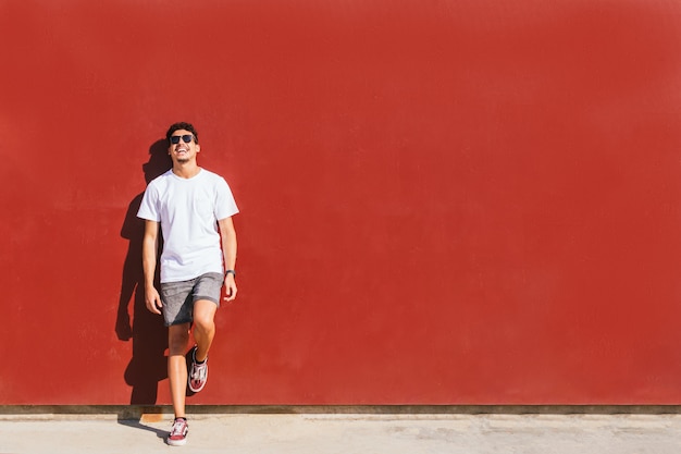 Young man smiling against a red wall