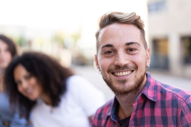 Young man smiling on camera having fun outdoor with multiracial friends in the city Focus on face