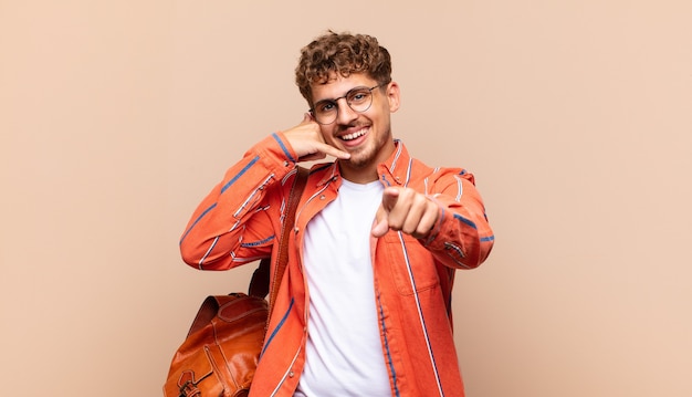 Young man smiling cheerfully and pointing to camera while making a call isolated