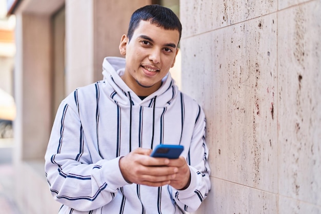 Young man smiling confident using smartphone at street