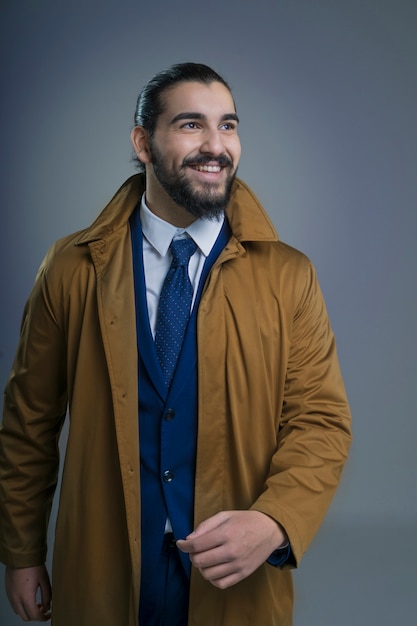 Young man smiling dressed in suit and raincoat