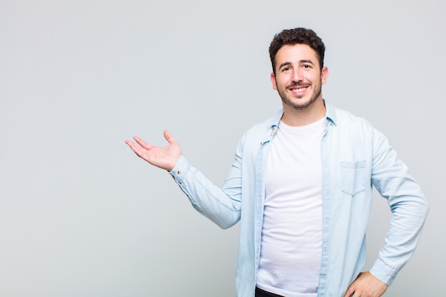 Young man smiling, feeling confident, successful and happy, showing concept or idea on copy space on the side