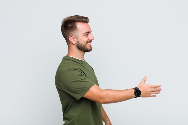 Photo young man smiling, greeting you and offering a hand shake to close a successful deal, cooperation concept