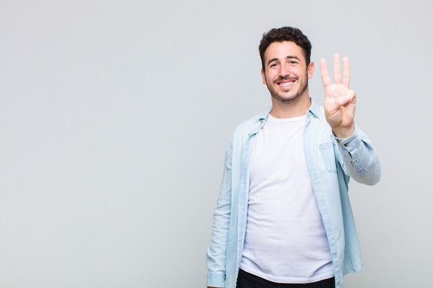 Young man smiling and looking friendly, showing number two or second with hand forward, counting down