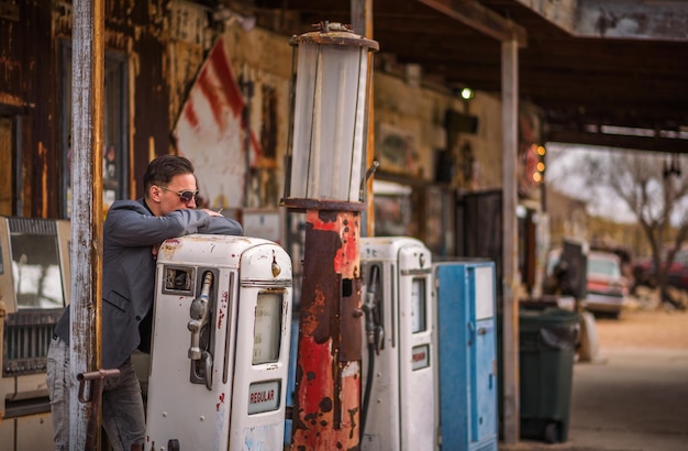 Young man smokes a cigarette at a vintage gas pump