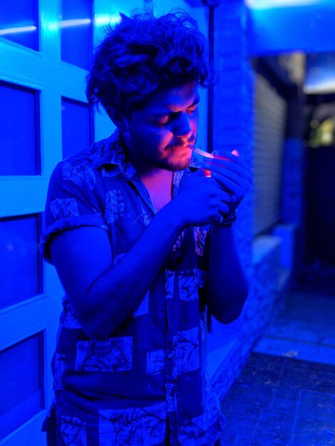 Photo young man smoking cigarette against wall