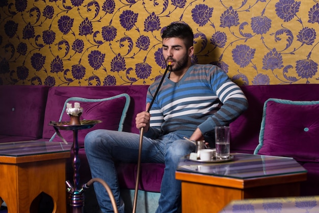 Young Man Smoking Shisha At Arabic Restaurant Man Exhaling Smoke Inhaling From A Hookah