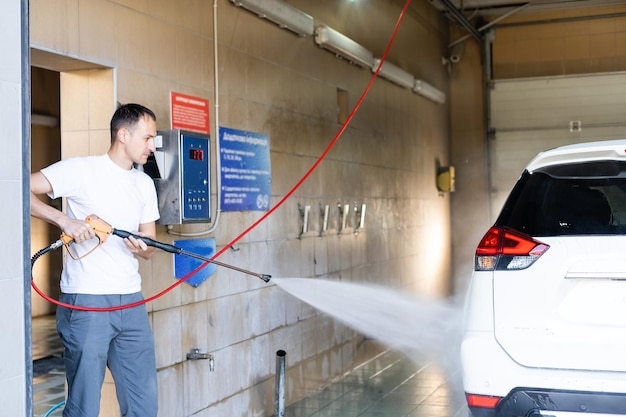 Young man spraying his car clean