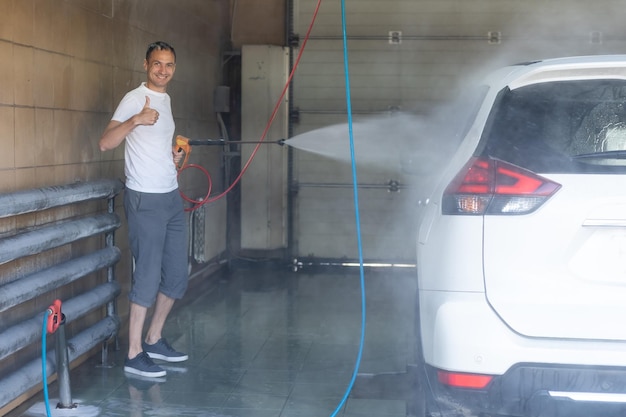 Young man spraying his car clean