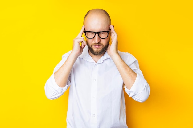 Young man squinting holding on to the weights on his head on a yellow background